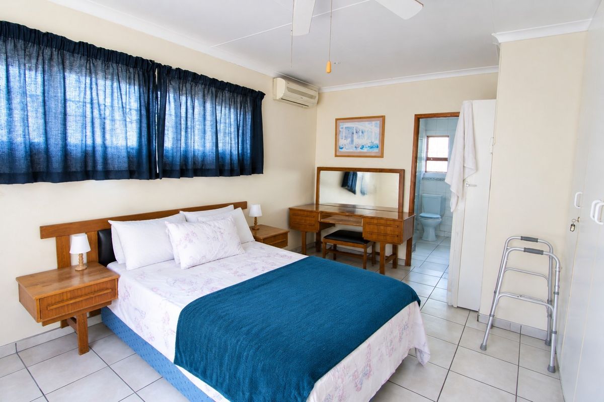 A well-maintained bedroom featuring tiled flooring, a ceiling fan, split-system air conditioning, and convenient access to an en-suite bathroom.