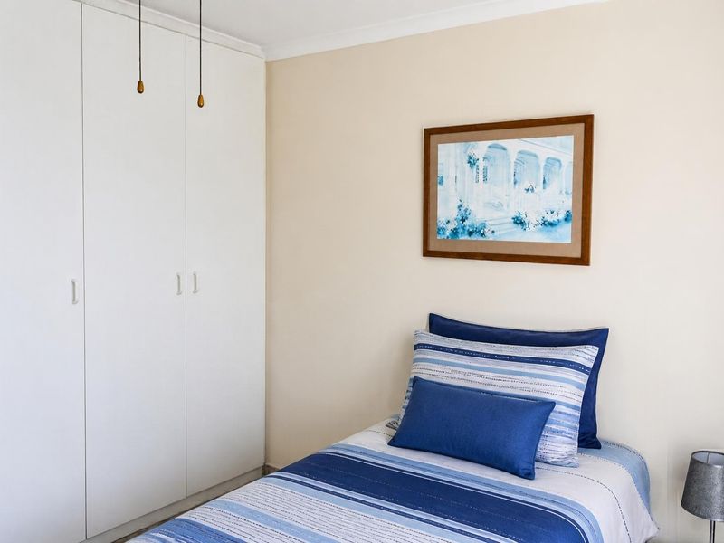 A well-maintained bedroom featuring neutral walls and practical built-in cupboards with clean finishes.