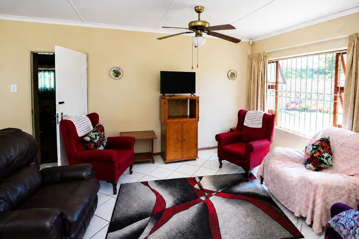 A living room featuring tiled flooring, a ceiling fan, and a large window with security bars, offering a functional and lived-in space.