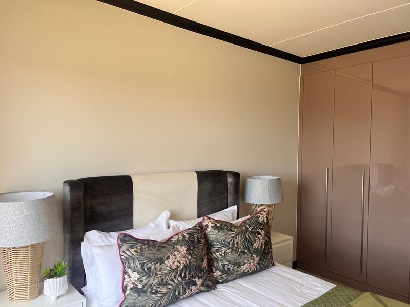 A well-maintained bedroom featuring a large, modern built-in wardrobe with a glossy finish and elegant crown molding.