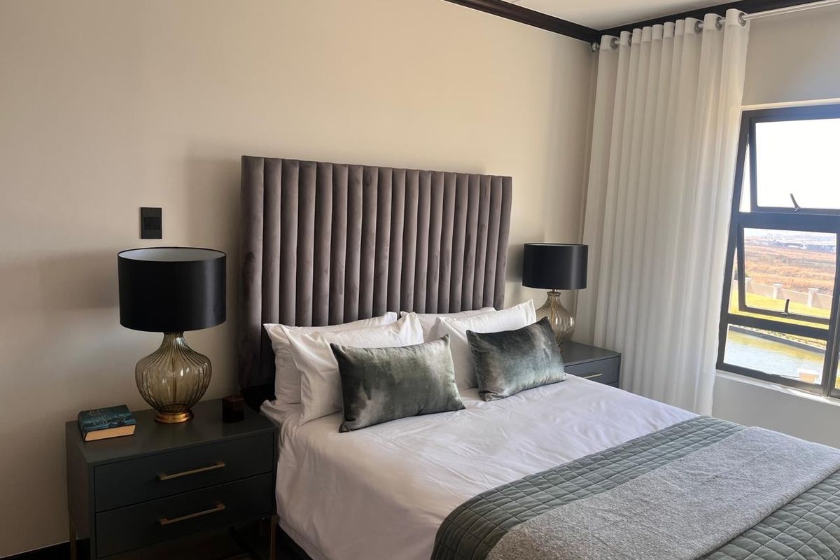 A well-maintained bedroom featuring neutral walls, crown molding, and a large window with natural light and views.