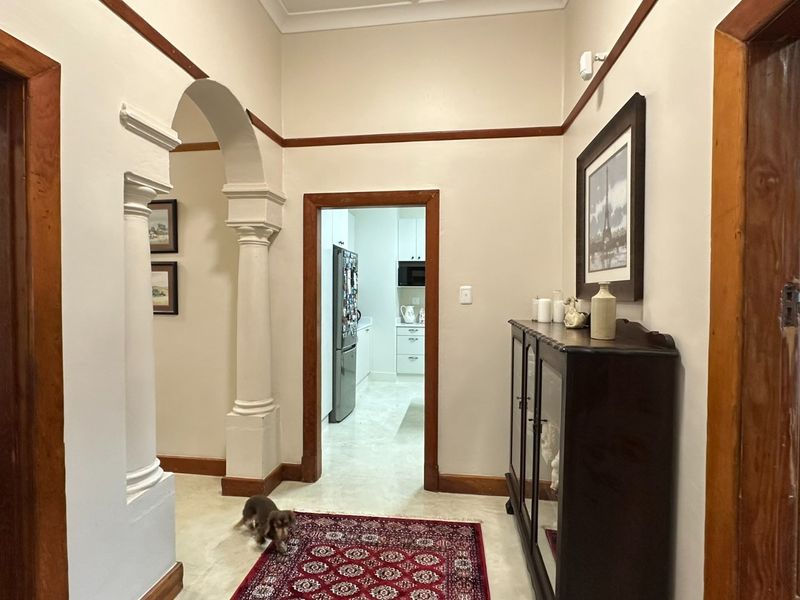 A well-maintained hallway featuring classic architectural details including an elegant archway with decorative columns, timber door frames, and traditional picture rails.