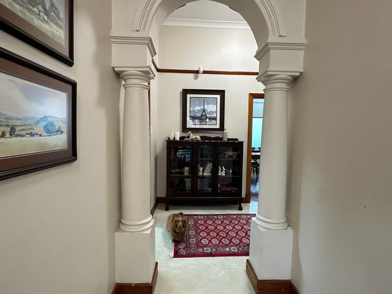A well-maintained hallway featuring a distinctive decorative archway supported by classical columns, creating a charming transition between living spaces.