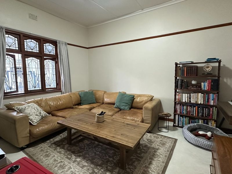 A comfortable living room featuring classic leaded glass windows, a decorative picture rail, and neutral tiled flooring.