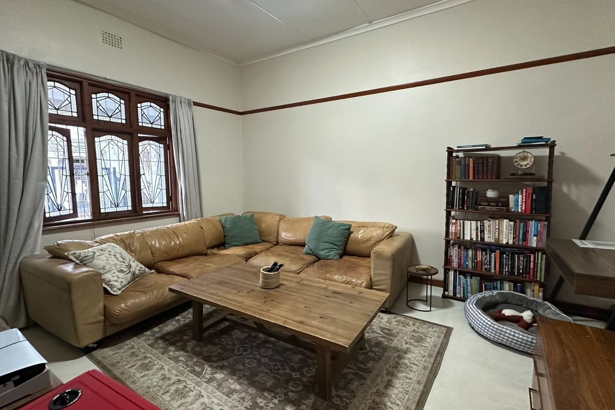 A comfortable living room featuring classic leaded glass windows, a decorative picture rail, and neutral tiled flooring.