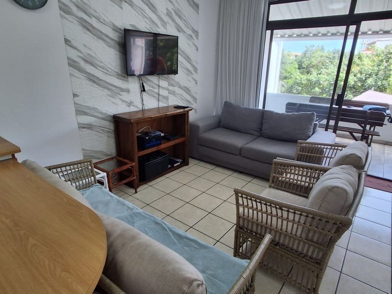 A living room area featuring tiled flooring, a textured feature wall, and a large sliding glass door providing access to an outdoor patio.
