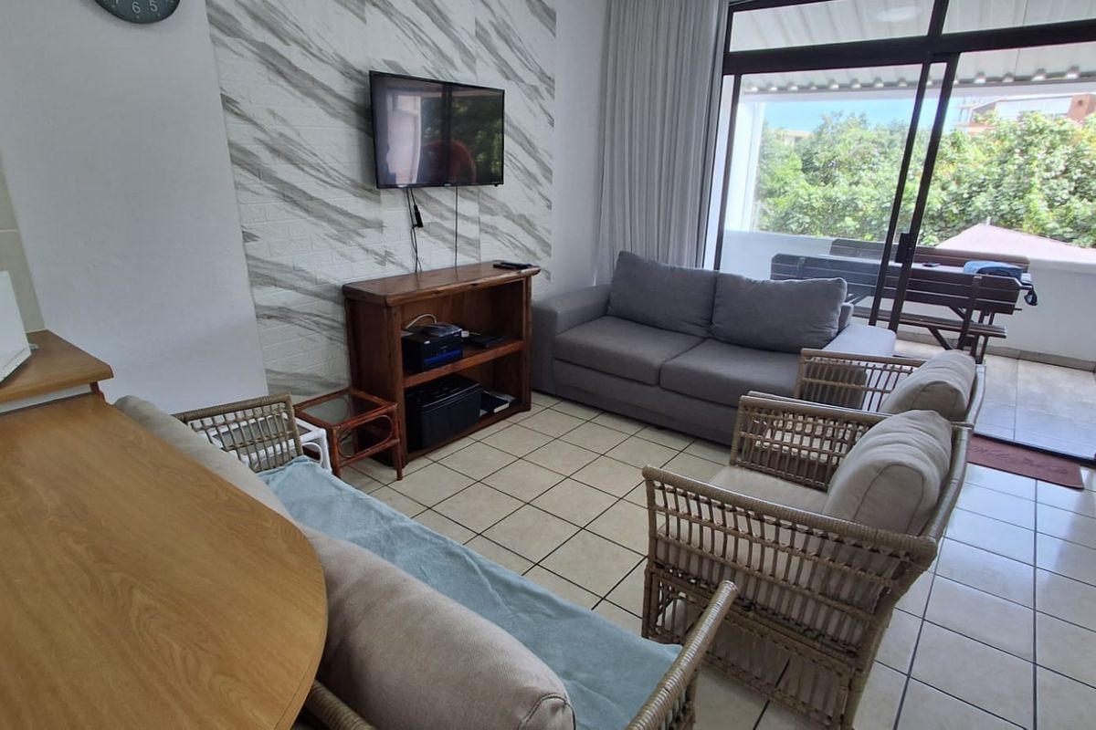 A living room area featuring tiled flooring, a textured feature wall, and a large sliding glass door providing access to an outdoor patio.