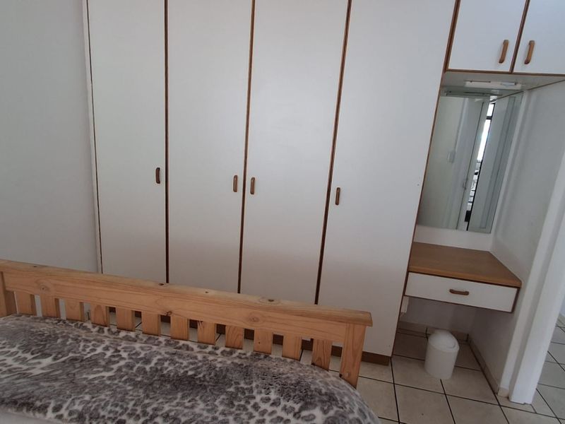 Bedroom featuring built-in white cupboards with integrated vanity unit and tiled flooring.