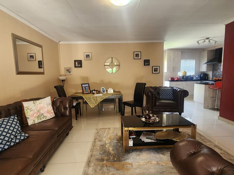 Spacious open-plan living and dining area featuring tiled floors and a modern kitchen with integrated cabinetry and a breakfast counter.