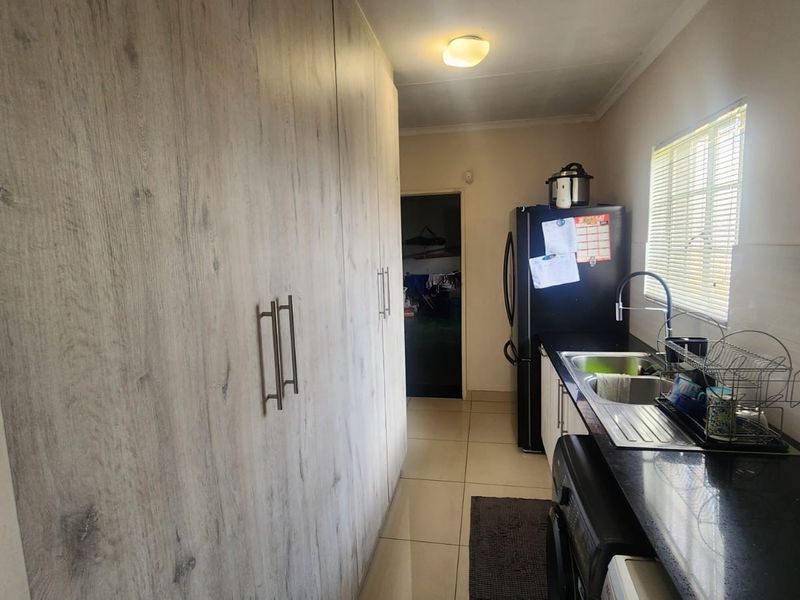A functional scullery area featuring extensive built-in cabinetry, a stainless steel sink, and tiled flooring, providing additional workspace and storage.