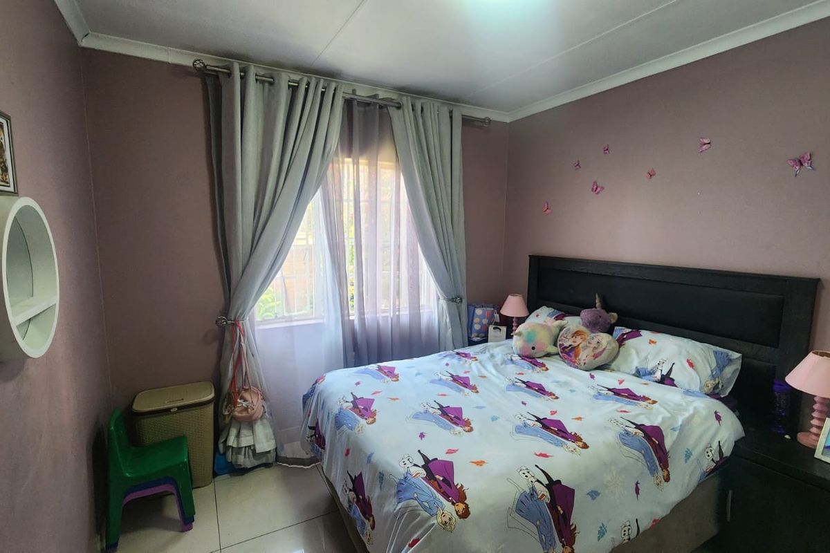 A functional bedroom featuring tiled flooring, a window with curtain treatments, and coved ceiling detailing.