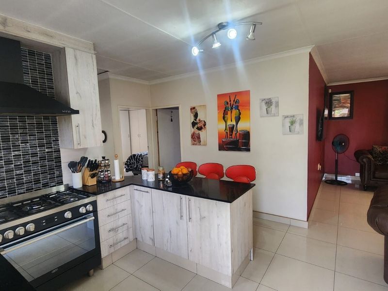 Open-plan kitchen and living area featuring a modern kitchen island, gas stove with extractor, tiled flooring, and neutral wall finishes.