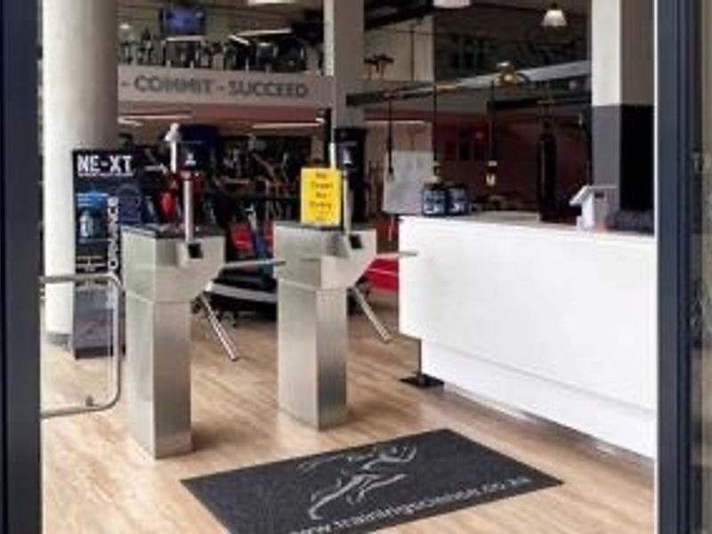 Entrance area of a professional sports facility featuring secure turnstile access control and a modern reception desk.