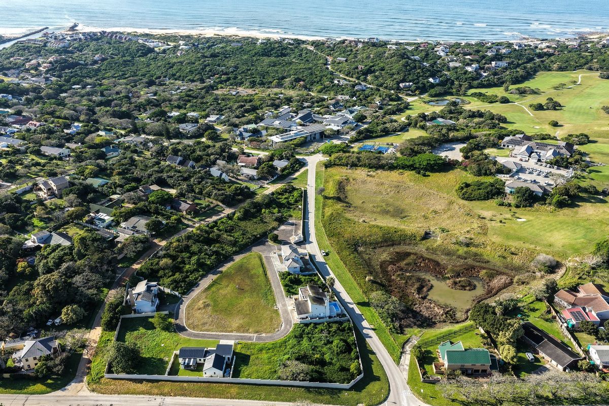 Aerial view of a residential estate featuring vacant land plots, established homes, and proximity to the coastline and natural vegetation.