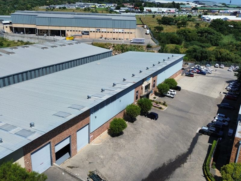 Aerial view of an industrial warehouse complex featuring metal roofing, multiple roller shutter doors, and a paved yard area.
