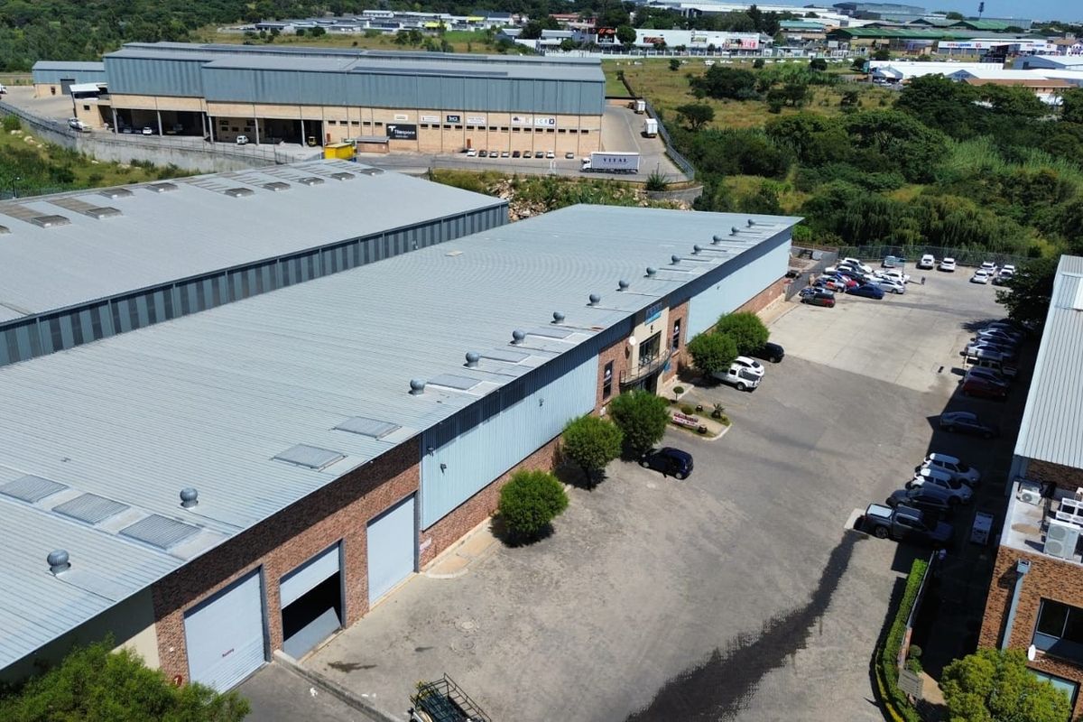 Aerial view of an industrial warehouse complex featuring metal roofing, multiple roller shutter doors, and a paved yard area.