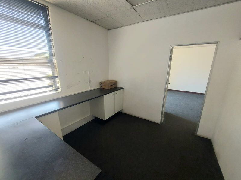 A functional office space featuring built-in desk cabinetry, carpeted flooring, and a suspended ceiling, offering a clean and professional environment for business operations.