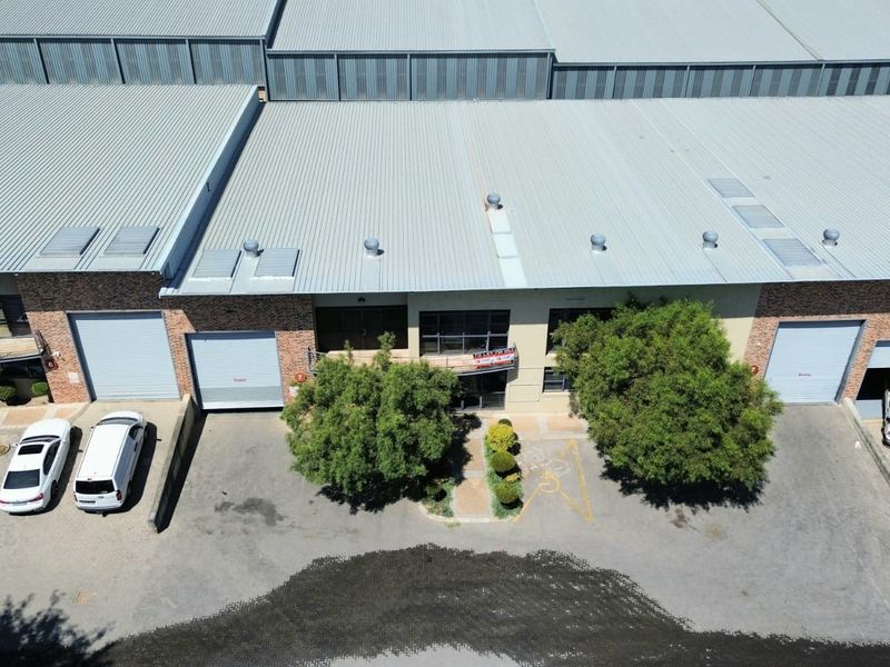 Aerial view of an industrial complex featuring corrugated metal roofing, multiple roller shutter doors, and dedicated asphalt parking bays.