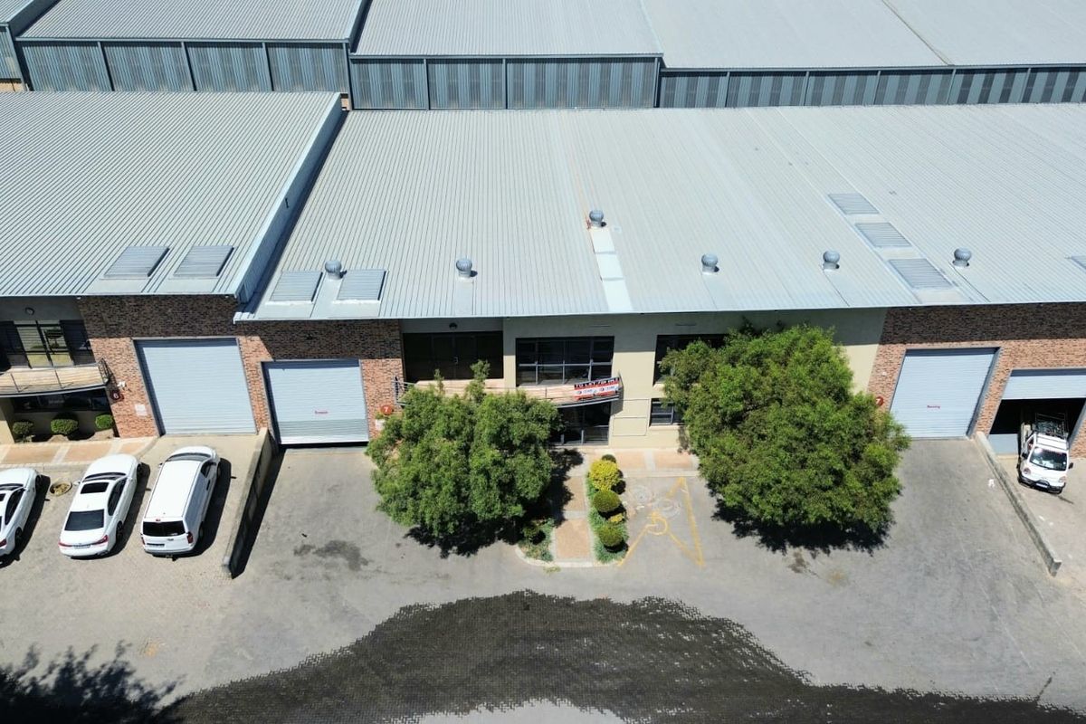 Aerial view of an industrial complex featuring corrugated metal roofing, multiple roller shutter doors, and dedicated asphalt parking bays.