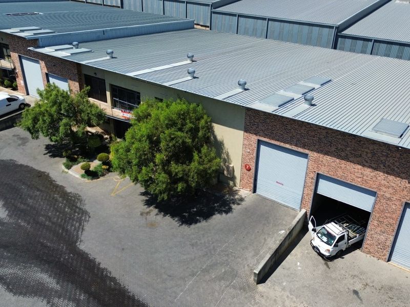 Aerial view of an industrial warehouse complex featuring brick facades, corrugated metal roofing, and multiple roller shutter access doors.