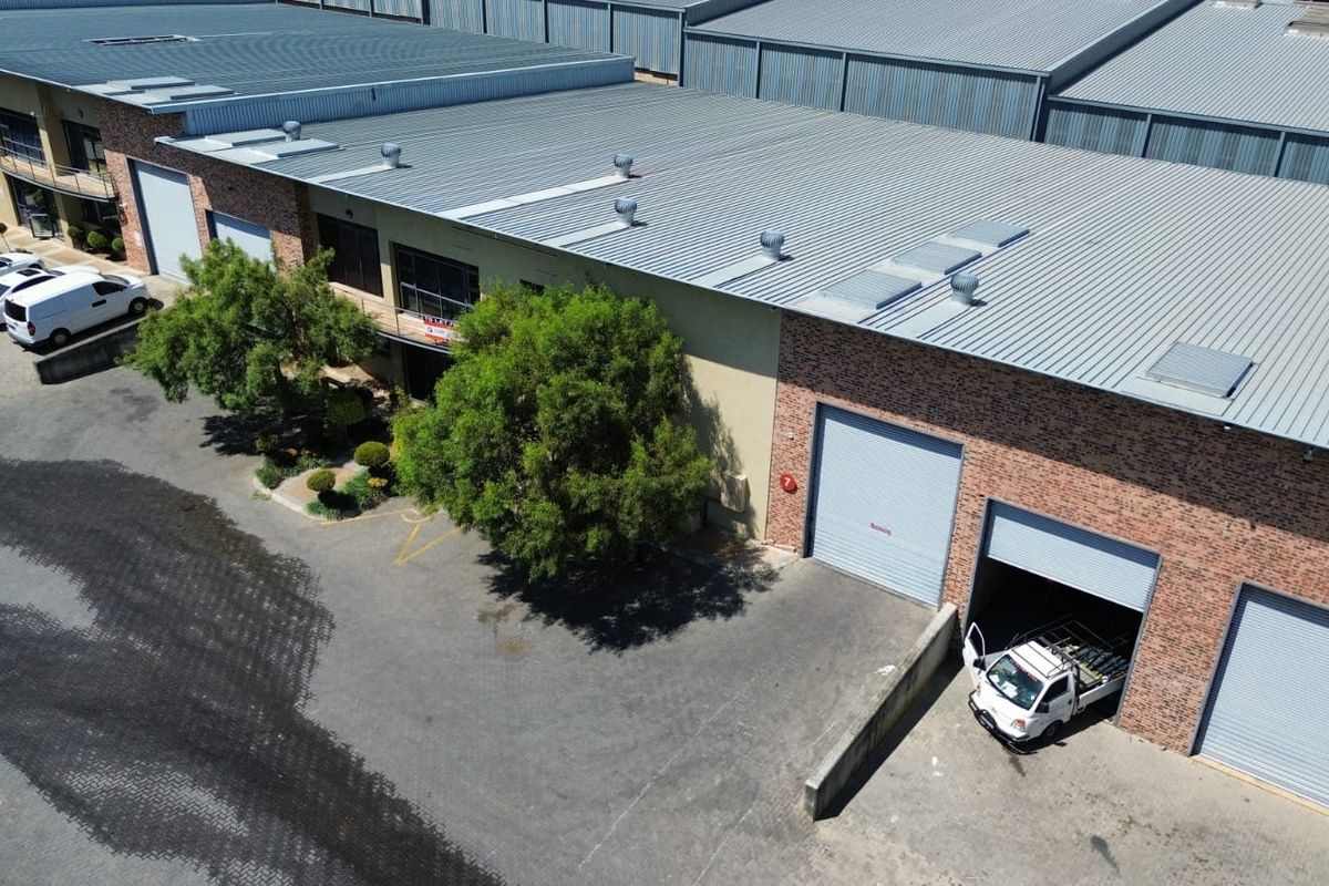 Aerial view of an industrial warehouse complex featuring brick facades, corrugated metal roofing, and multiple roller shutter access doors.