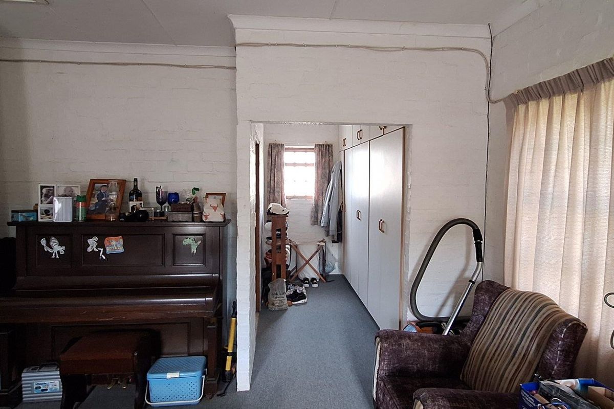 Living area featuring exposed brick walls, built-in storage cupboards, and carpeted flooring, with visible surface-mounted electrical conduit requiring attention.