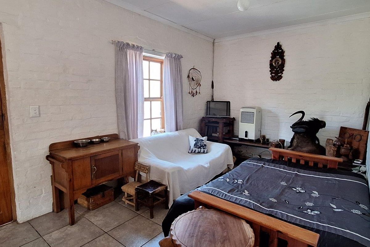 A bedroom featuring painted brick walls, tiled flooring, and a timber door, offering a rustic aesthetic that could benefit from modern updates.