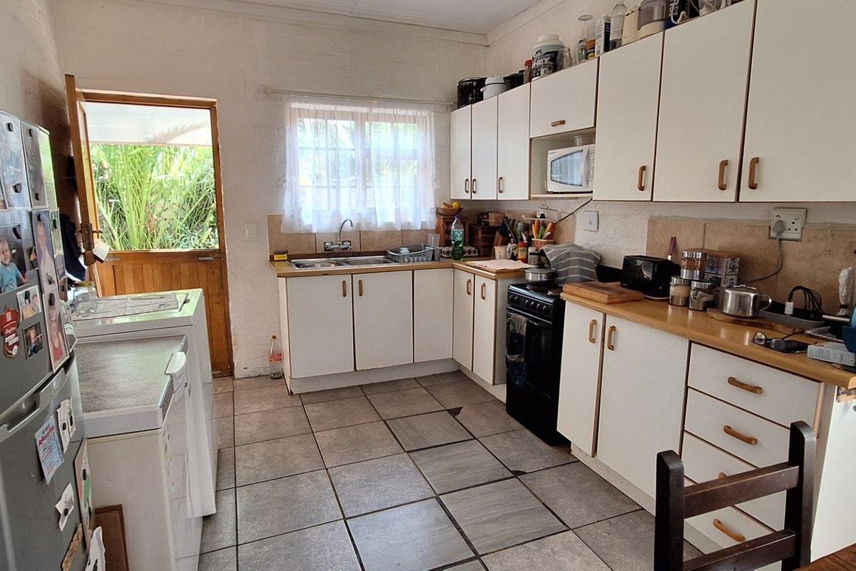 Functional kitchen featuring white cabinetry, laminate countertops, tiled flooring, and direct access to the rear exterior.