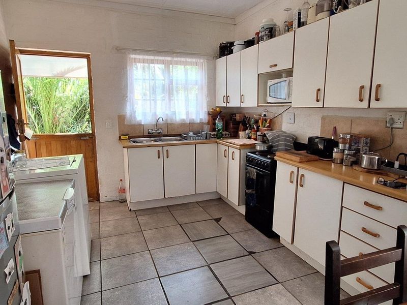 Functional kitchen featuring white cabinetry, laminate countertops, tiled flooring, and direct access to the rear exterior.