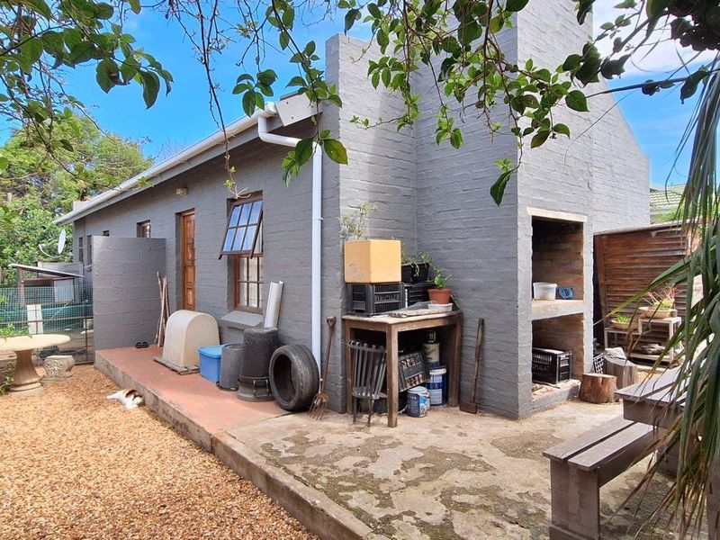 Rear exterior view of the townhouse featuring a concrete patio, built-in braai area, and gravel garden space.