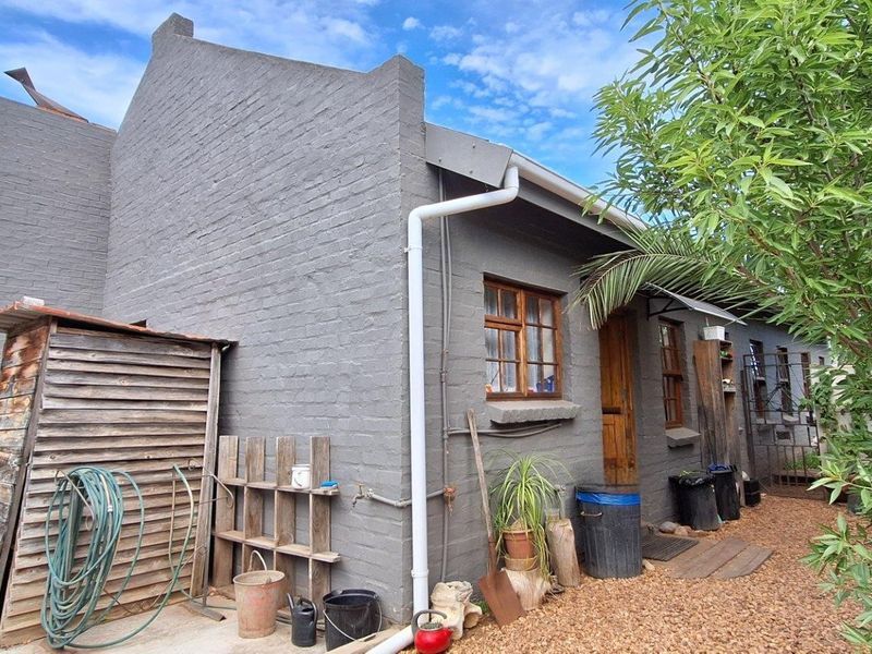 Rear exterior view of the townhouse featuring painted brick walls, timber window frames, and functional guttering systems.