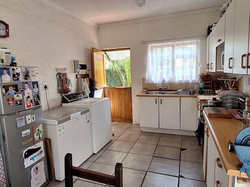 Functional kitchen featuring white cabinetry, tiled flooring, a double sink, and a stable door providing direct access to the exterior.