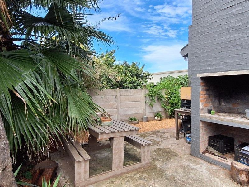 Rear courtyard area featuring a built-in brick braai, concrete paving, and a precast boundary wall, offering a functional outdoor entertainment space.