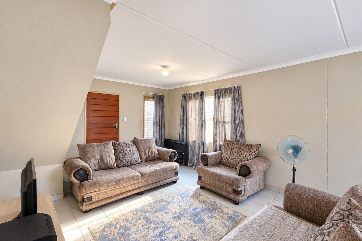 A well-lit living room featuring neutral wall tones, tiled flooring, and a coved ceiling, providing a comfortable and functional space for relaxation.