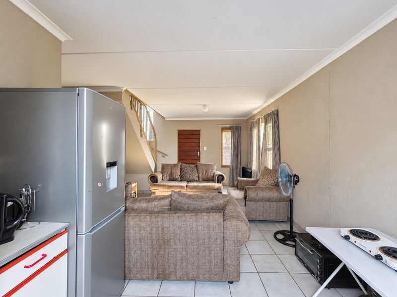 An open-plan living area featuring tiled flooring and a staircase, connecting the kitchen space with the main lounge area.