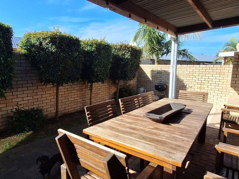 A covered outdoor patio area featuring paved flooring and brick boundary walls, providing a private space for outdoor dining and relaxation.