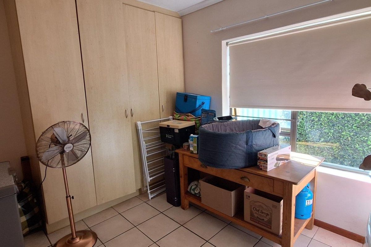 A bedroom featuring built-in cupboards, tiled flooring, and a window with a roller blind, offering a functional space with potential for modernization.