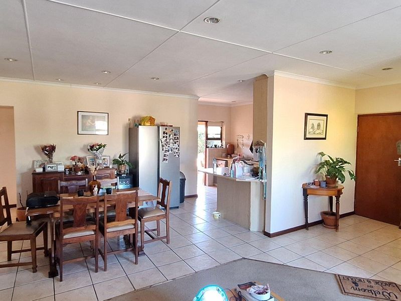 Spacious open-plan living and dining area featuring tiled flooring, recessed lighting, and a functional kitchen breakfast counter layout.