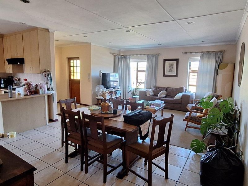 Open-plan living, dining, and kitchen area featuring tiled flooring, recessed lighting, and a functional kitchen layout with a breakfast bar.