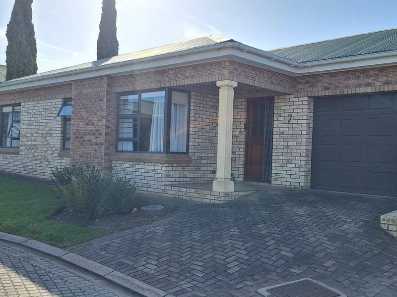 Front elevation of a face brick townhouse featuring a paved driveway, single garage, and a covered entrance porch.