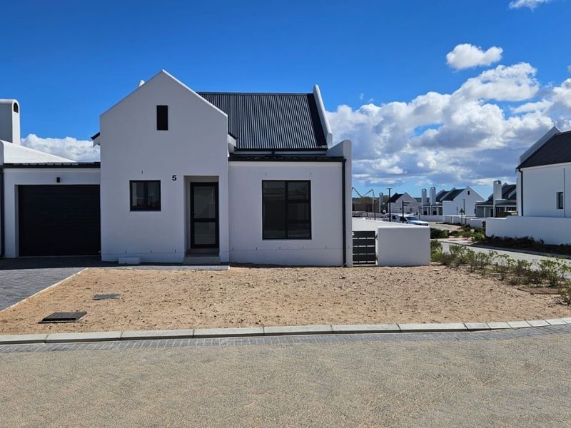 Modern single-story home featuring a gabled roof, clean white facade, and paved driveway in a contemporary residential estate.
