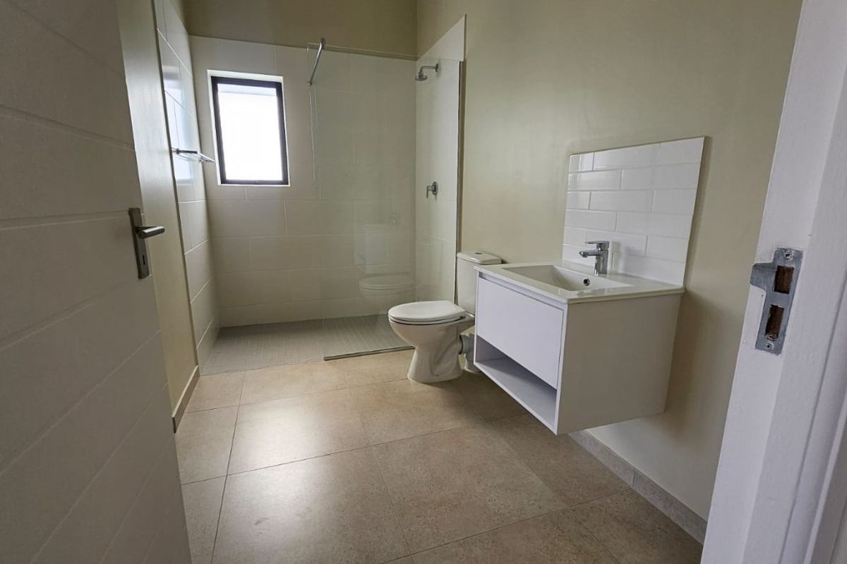 A clean, modern bathroom featuring a wall-mounted vanity, subway tile splashback, and a walk-in shower with a glass screen.
