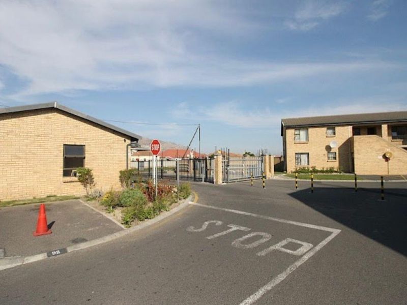 Exterior view of the apartment complex entrance featuring paved driveway, brick building facade, and secure gated access.