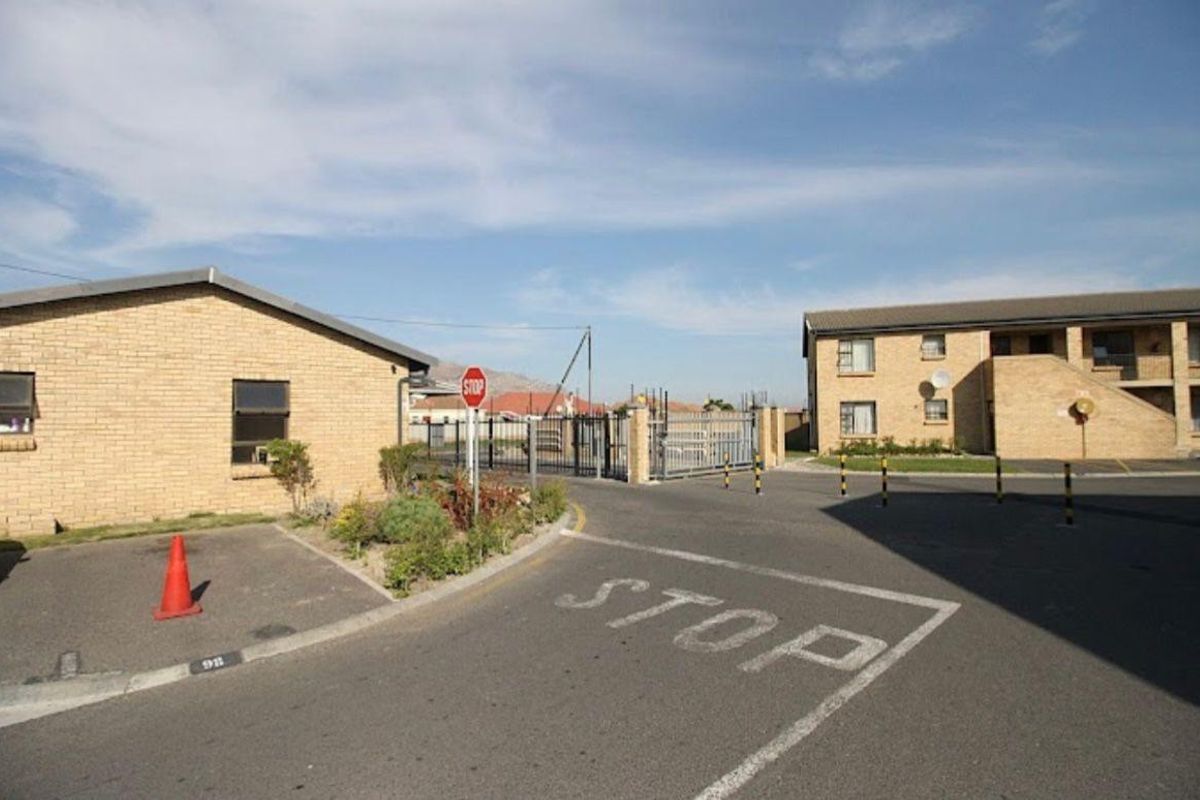 Exterior view of the apartment complex entrance featuring paved driveway, brick building facade, and secure gated access.