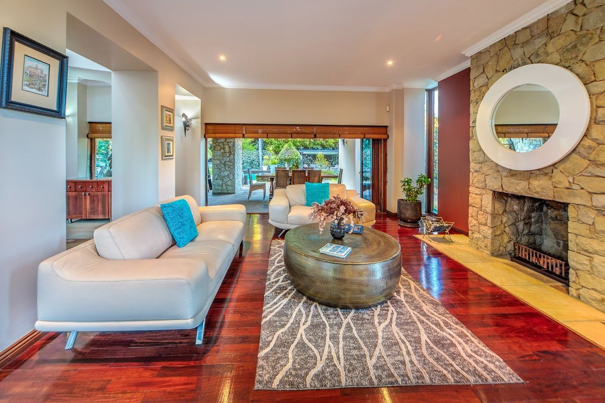 Spacious living room featuring polished hardwood floors, a prominent stone fireplace, and large sliding glass doors that open to an outdoor patio area.