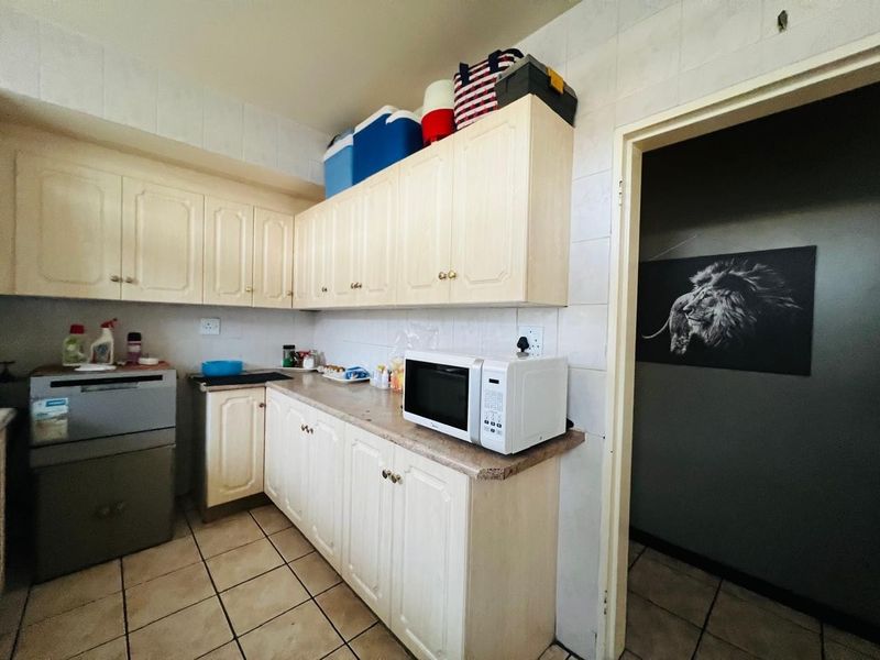 A functional kitchen featuring light-toned cabinetry, laminate countertops, and tiled splashbacks, offering a practical layout for daily meal preparation.