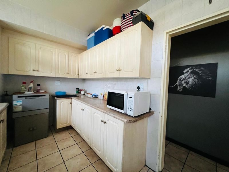 A functional kitchen featuring laminate cabinetry, tiled walls, and tiled flooring, offering a dated aesthetic with potential for modern renovation.