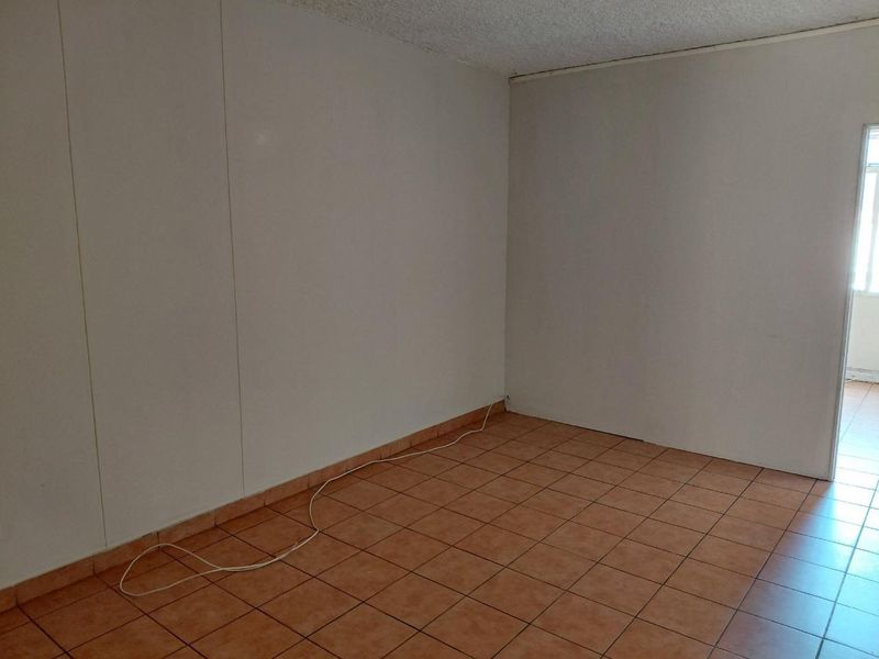 An empty living area featuring ceramic tile flooring and textured ceilings, offering a blank canvas for potential interior design and renovation.