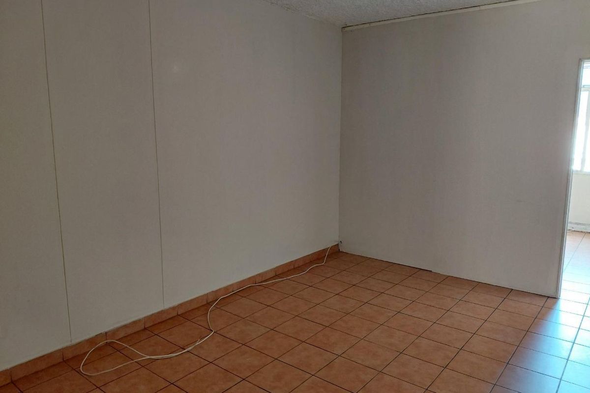 An empty living area featuring ceramic tile flooring and textured ceilings, offering a blank canvas for potential interior design and renovation.