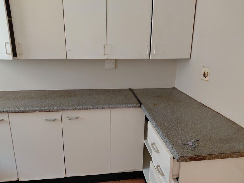 A functional kitchen area featuring white built-in cabinetry and laminate countertops, offering a blank canvas for potential renovation and modernization.